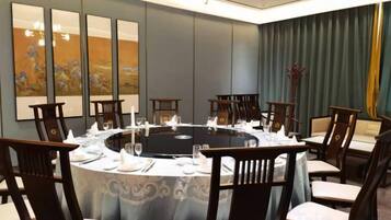 Un salón de conferencias con una mesa redonda, sillas y un mantel.