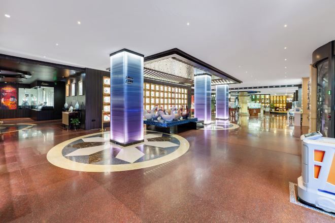 A spacious lobby with a central seating area, a reception desk, and a modern design with illuminated pillars.