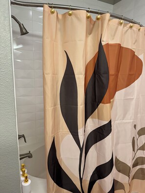 Shower area features a geometric leaf-patterned curtain and a showerhead.