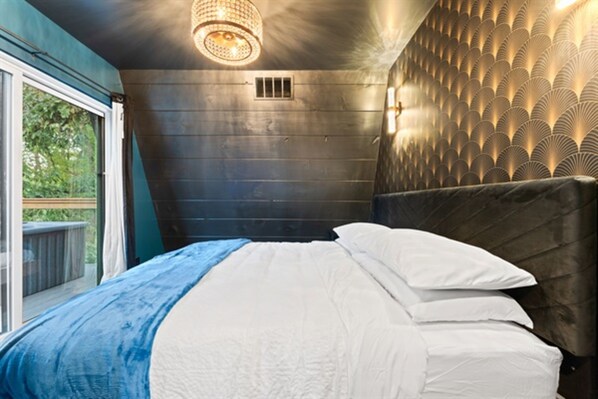 A bedroom with a large bed, a view of the outdoors, and a unique wall design.