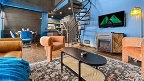A modern living room with a fireplace, a staircase, and a dining area. - Adults-Only Luxury Cabin w/ Steam Shower + HotTub (Omaha)