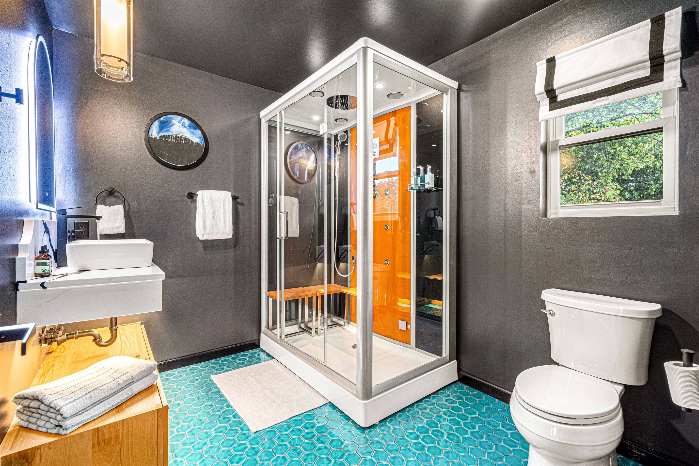 A modern bathroom with a glass-enclosed shower, a white toilet, and a sink with a mirror.