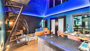 A modern kitchen with a dining area, a staircase, and a view of the city.