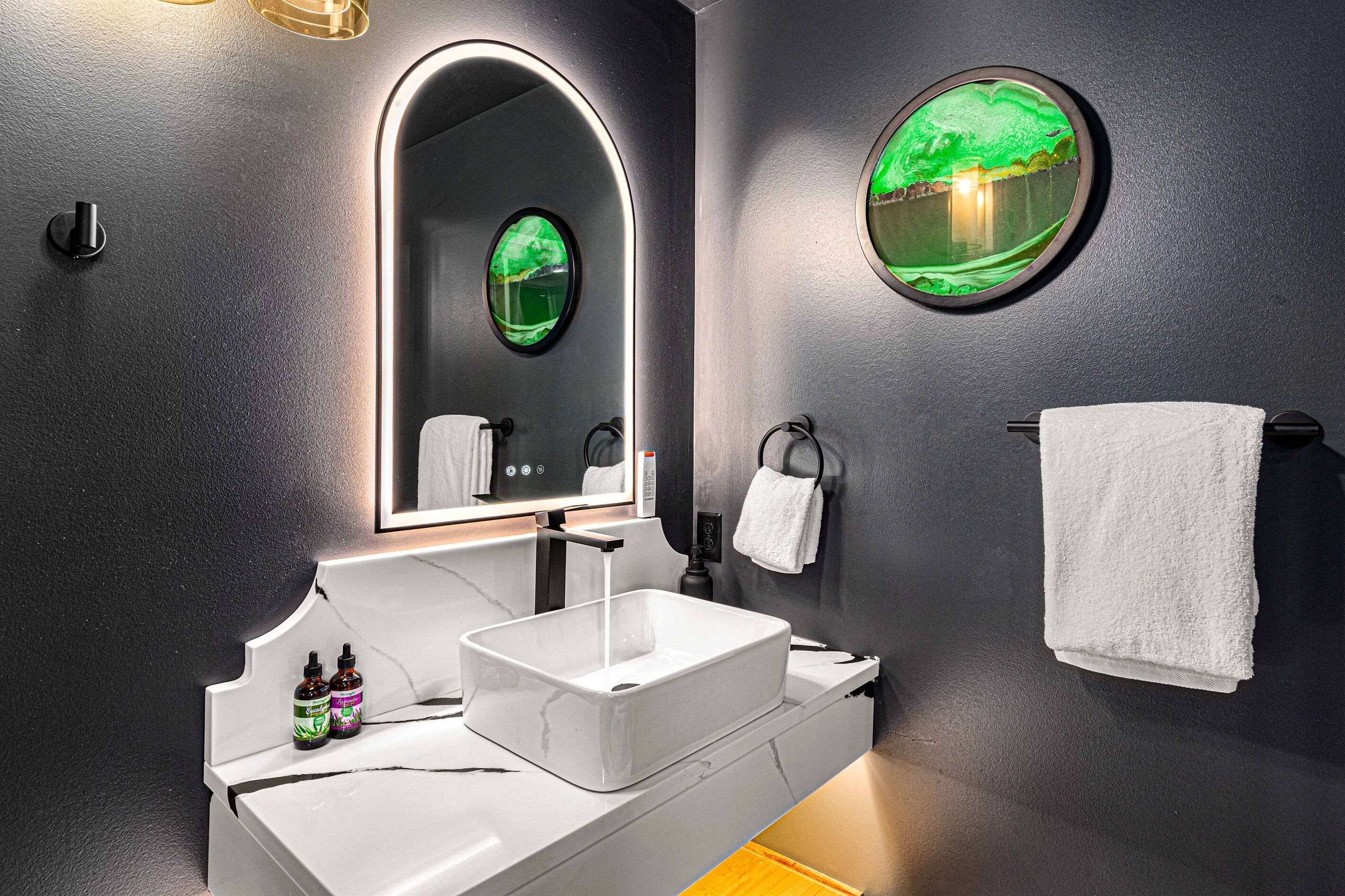 Une salle de bain moderne avec un lavabo blanc, un miroir avec un cadre vert et un porte-serviettes.