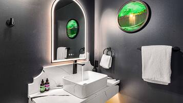 Une salle de bain moderne avec un lavabo blanc, un miroir avec un cadre vert et un porte-serviettes.