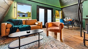 Een modern loft met hoge plafonds, een groot raam en een gezellige zithoek met een bank en fauteuil.