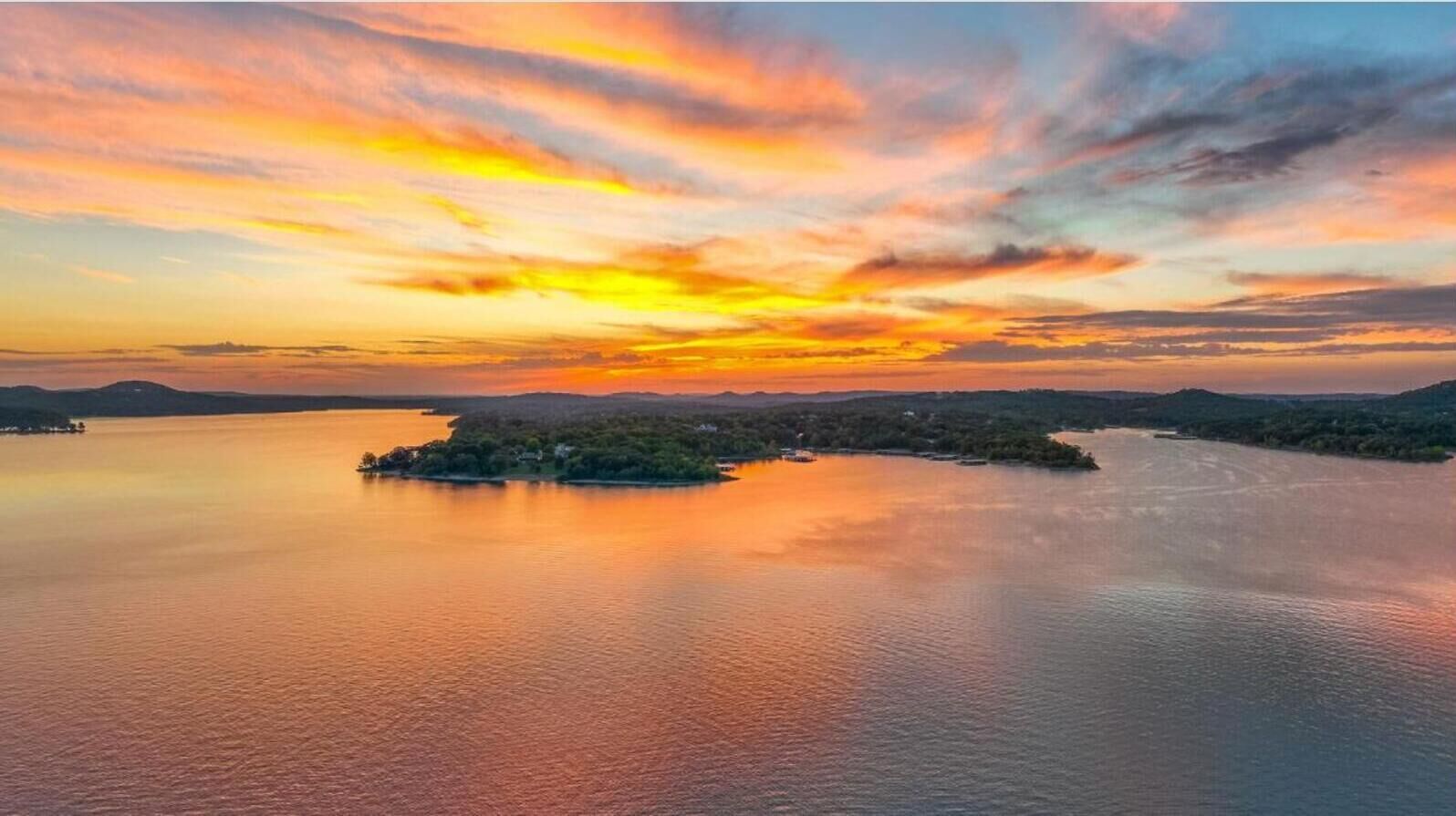 A sunset over a calm body of water with a small island in the center.