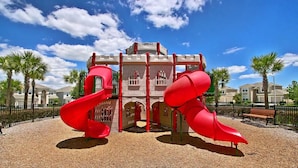 A playground with two red slides and a castle-like structure. - Windsor Hills  Charming 3BR Condo, Pool, By Disney (Kissimmee)