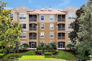 A multi-story residential building with a symmetrical facade, balconies, and a well-maintained garden. - Windsor Hills 3BR: Themed Rooms, Disney (Kissimmee)