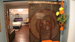 A room with a brick floor, a bed, a chair, and a decorative partition with a circular design.