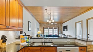 A kitchen with wooden cabinets, a dishwasher, a granite countertop, and a stone backsplash.
