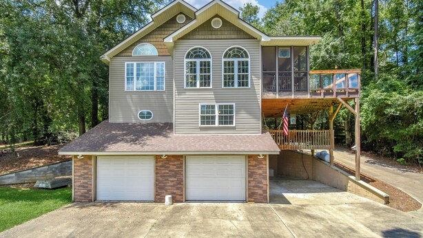 Une maison à deux étages avec un garage, une véranda et une terrasse.