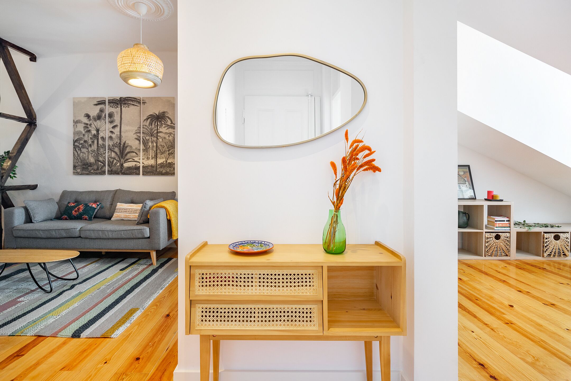 Un salon moderne avec un canapé, une table basse, une console avec un miroir et un plancher en bois.