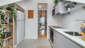 Een kleine keuken met witte kastjes, een roestvrijstalen spoelbak en een houten aanrecht.