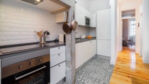 Una cocina moderna con armarios blancos, encimera negra y suelo estampado.