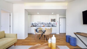 A modern living room with a sofa, a wooden coffee table, and a dining area with chairs and a table. - Alcântara Premium Apartment (Lisbon)