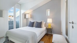 A modern bedroom with a large bed, bedside lamps, and a view through a window. - Alcântara Premium Apartment (Lisbon)