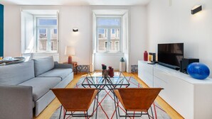A modern living room with a sofa, a glass coffee table, and a TV on a white cabinet. - Alecrim 43 Top Location Perfect To Explore Lisbon (Lisbon)