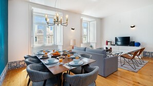 A modern living room with a dining area, large windows, a flat-screen TV, and a sofa. - Alecrim 43 Top Location Perfect To Explore Lisbon (Lisbon)