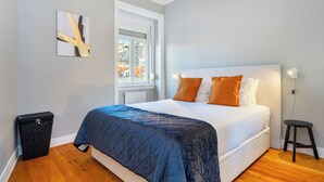A bedroom with a bed, a window, a wall-mounted artwork, and a trash bin. - Aq2 Prime Location Luxury For Family & Friends (Lisbon)