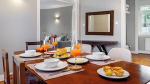 A dining area with a wooden table set for breakfast, including croissants, orange juice, and pastries. - Aq2 Prime Location Luxury For Family & Friends (Lisbon)