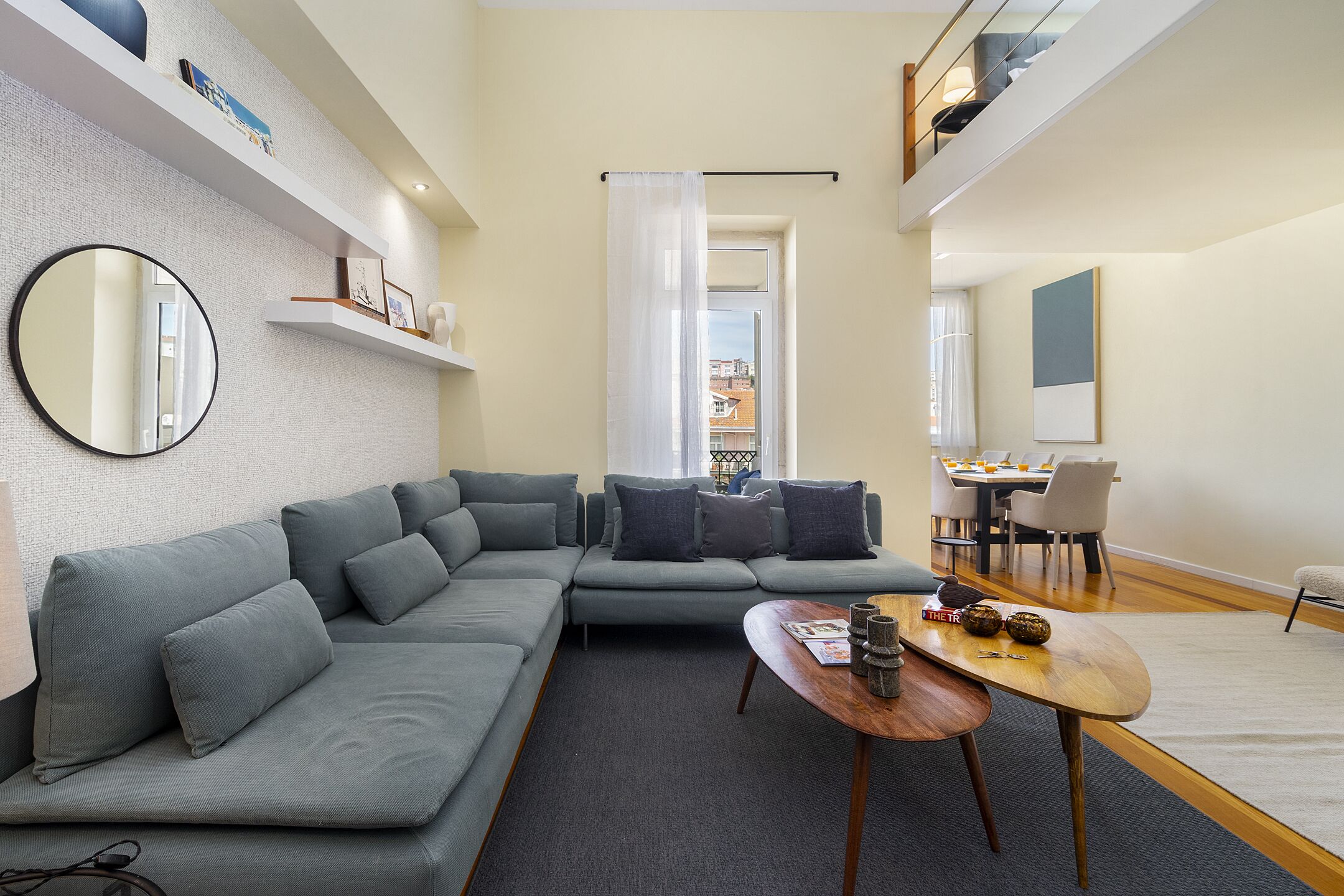 Un saló modern amb un sofà modular, una taula de centre de fusta i una zona de menjador amb taula i cadires.