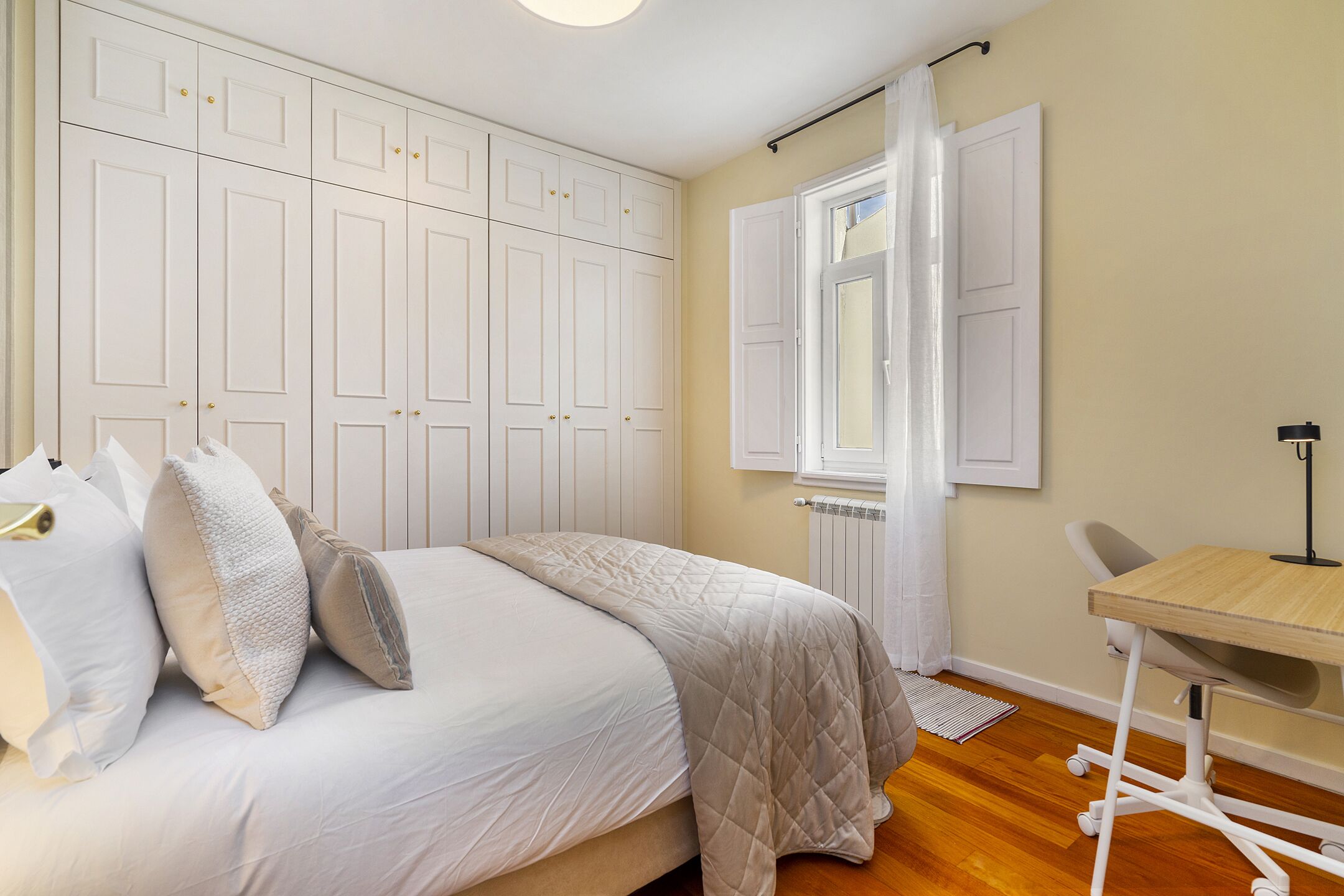 A bedroom with a bed, a desk, and a wardrobe.