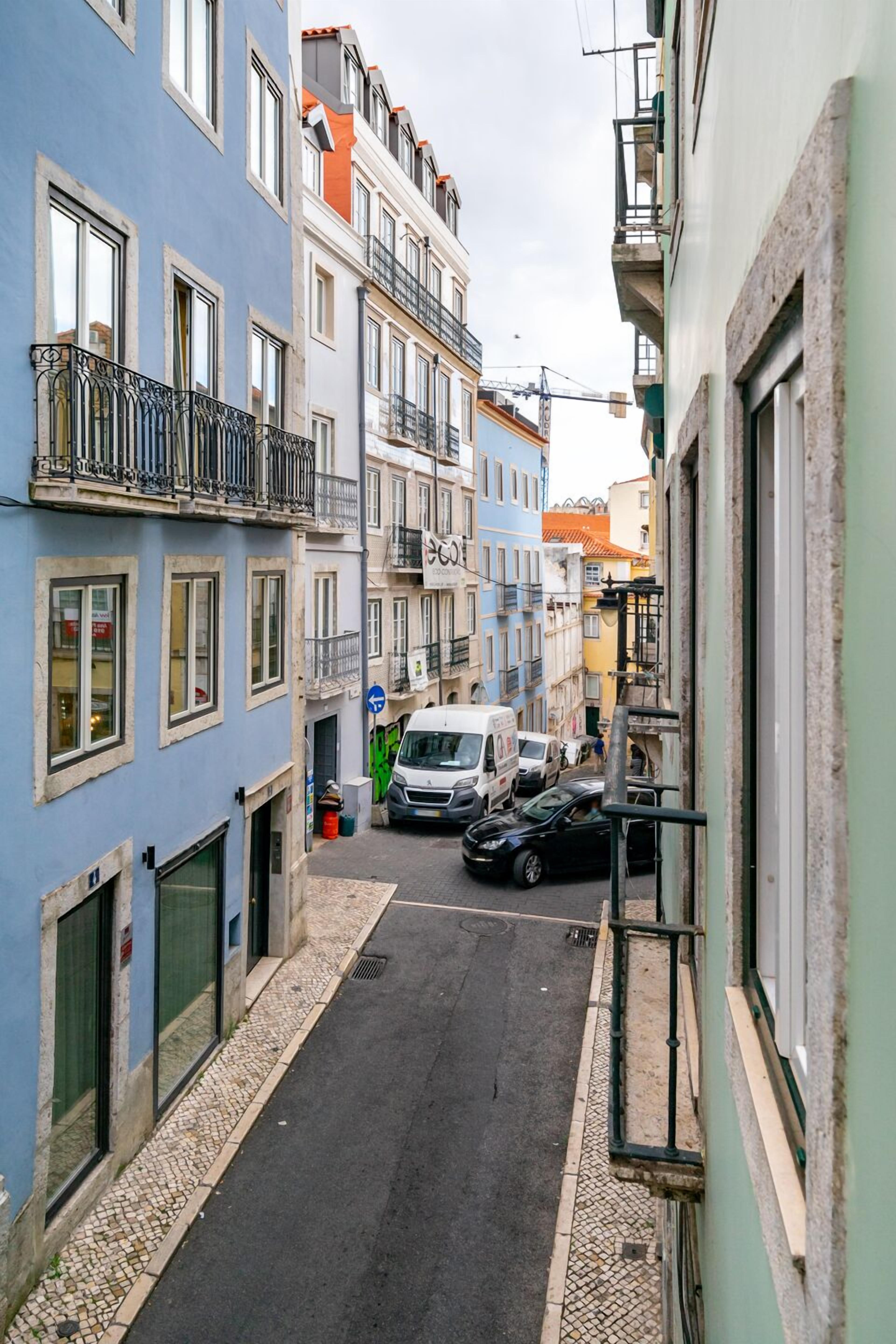Une rue étroite bordée de bâtiments des deux côtés, avec des balcons et un mélange de styles architecturaux.