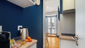 A modern kitchen with a coffee maker, a kettle, and a fruit bowl.