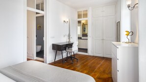 Ein Schlafzimmer mit einem Bett, einem Schreibtisch und einem Stuhl. Durch eine geöffnete Tür ist ein Badezimmer zu sehen.