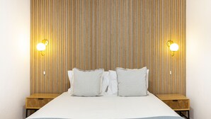 Ein Bett mit Holz-Kopfteil, zwei Nachttische und zwei Wandleuchten.