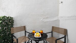 Ein kleiner runder Tisch mit zwei Stühlen, einem Teller mit Essen und zwei Gläsern Orangensaft.