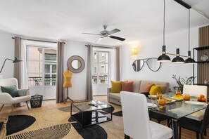 Una sala de estar moderna con una mesa de centro de vidrio, un sofá y una mesa de comedor lista para el desayuno.