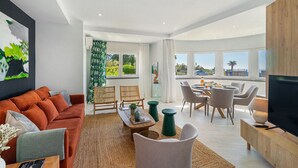 Una sala de estar moderna con un sofá, sillas, una mesa de comedor y un televisor.