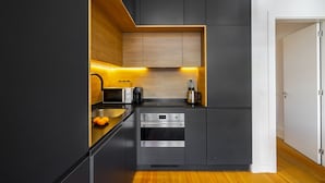 A modern kitchen with dark cabinetry, a built-in oven, and a wooden countertop. - Urban Elegance: A Modern Haven In Lisbon'S Heart (Lisbon)