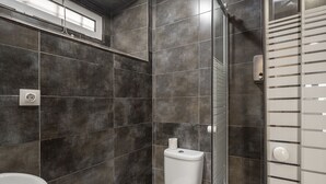 A bathroom with dark tiles, a white toilet, and a sink. - Cozy Alfama Haven: Perfect For Exploring Lisbon (Lisbon)