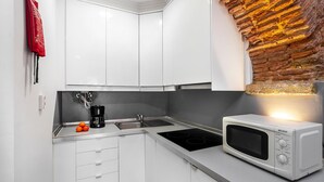 A modern kitchen with white cabinets, a built-in stove, and a microwave. - Cozy Alfama Haven: Perfect For Exploring Lisbon (Lisbon)