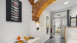 A hotel corridor with a dining area featuring a table with breakfast, a wall art of fish, and a unique brick ceiling design. - Cozy Alfama Haven: Perfect For Exploring Lisbon (Lisbon)