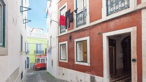 Une rue étroite, bordée de bâtiments des deux côtés, un tramway rouge et du linge qui sèche sur un balcon.