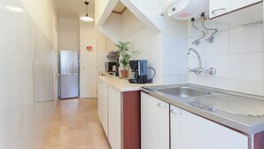 Une cuisine moderne avec des armoires blanches, un évier en acier inoxydable et un four encastré.