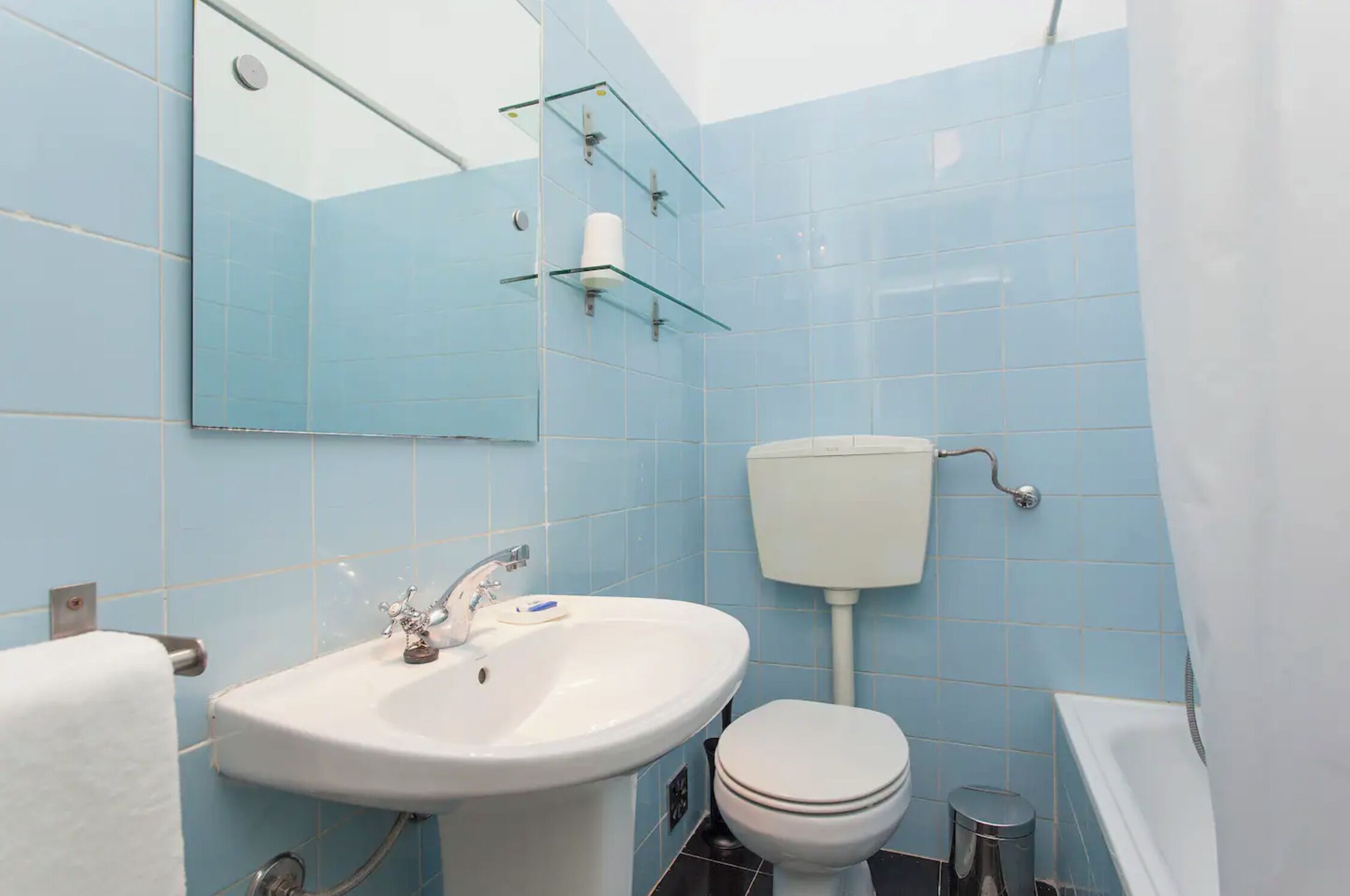 Een badkamer met een wit wastafelmeubel, toilet en bad.