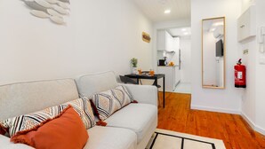 Ein modernes Wohnzimmer mit einer Couch, einem Couchtisch und einer Küchenzeile im Hintergrund.