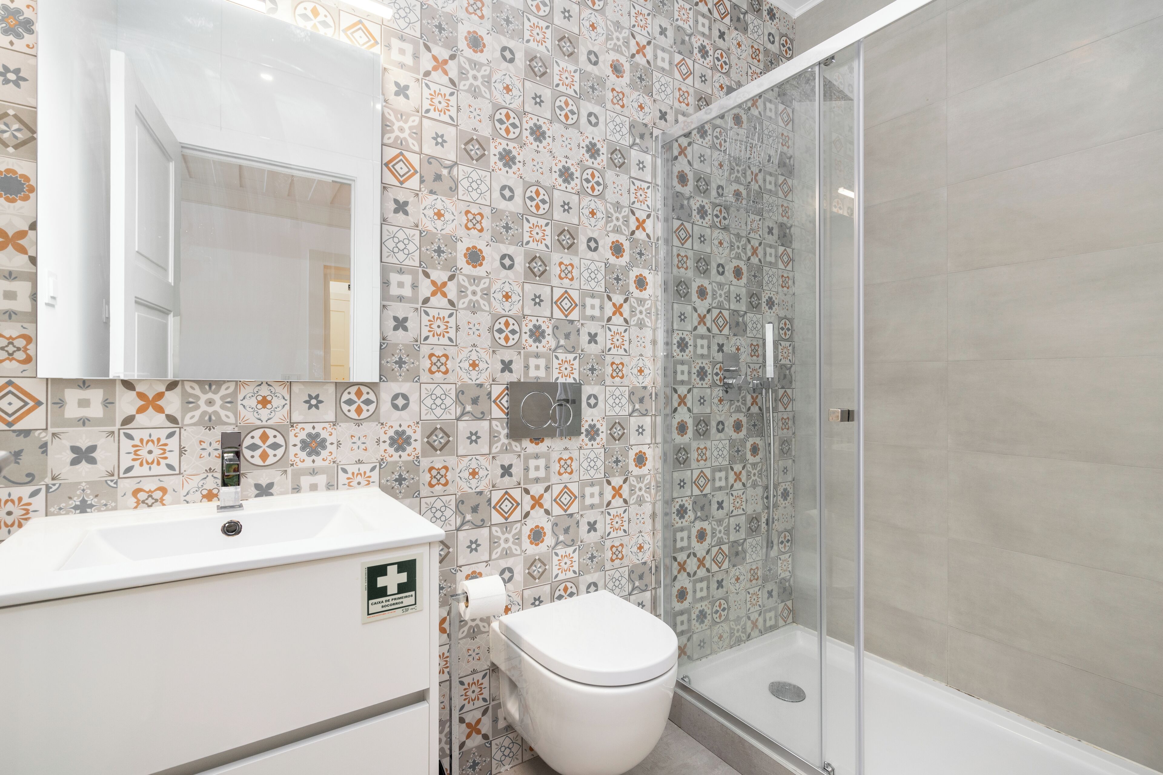 Un baño con ducha, inodoro, lavabo y espejo.