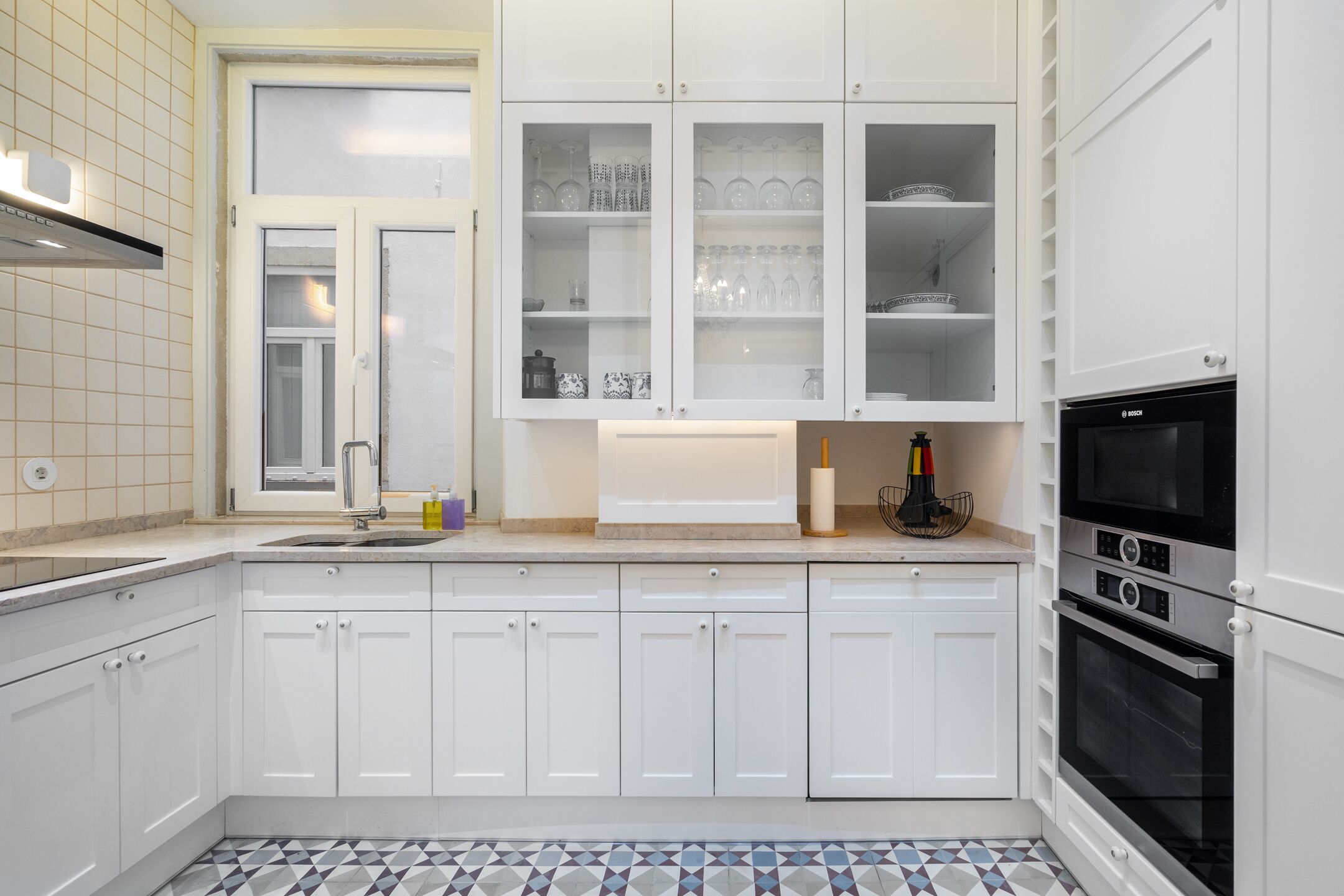 A modern kitchen with white cabinets, a built-in oven, and a tiled backsplash.