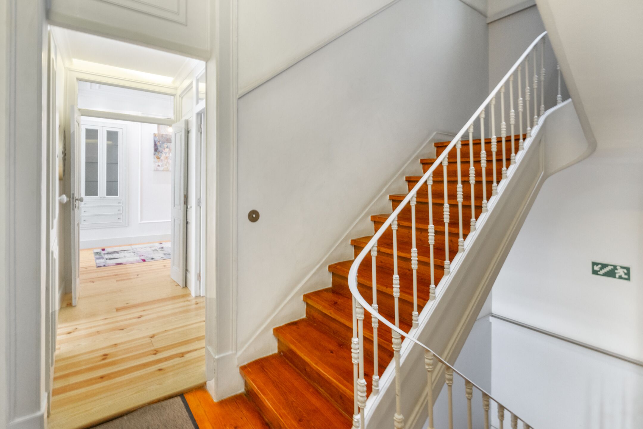 A staircase with wooden steps and white balusters, leading to a landing with a white door.