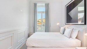 A modern hotel room with a large bed, a view of the city through a window, and a framed artwork on the wall. - The Boulevard Prime Location W/ Elevator (Lisbon)