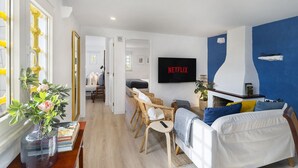 Un salon moderne avec un canapé, une table basse et un téléviseur affichant le logo « NETFLIX ».