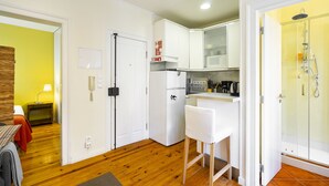 Une cuisine de taille réduite, avec des meubles blancs, un réfrigérateur et un petit plan de travail.