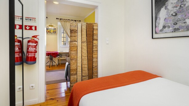 Une chambre à coucher comprenant un lit, un extincteur et une porte donnant sur un coin repas.