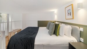 A neatly made bed with a black and white duvet, a wooden nightstand, and a framed picture on the wall. - Lisbon'S Elite A Stylish & Modern Studio W Patio (Lisbon)